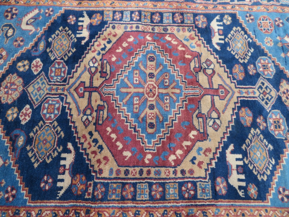 An antique blue-ground hand-knotted Turkish Kurdish tribal wool rug featuring a central geometric medallion and stylized animal motifs. View VIII