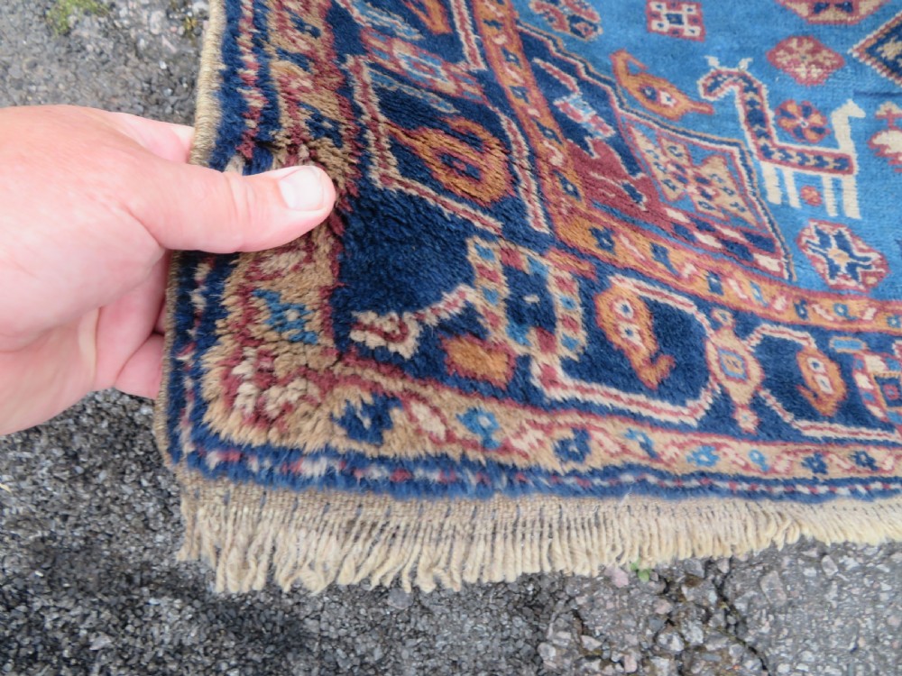 An antique blue-ground hand-knotted Turkish Kurdish tribal wool rug featuring a central geometric medallion and stylized animal motifs. View IX