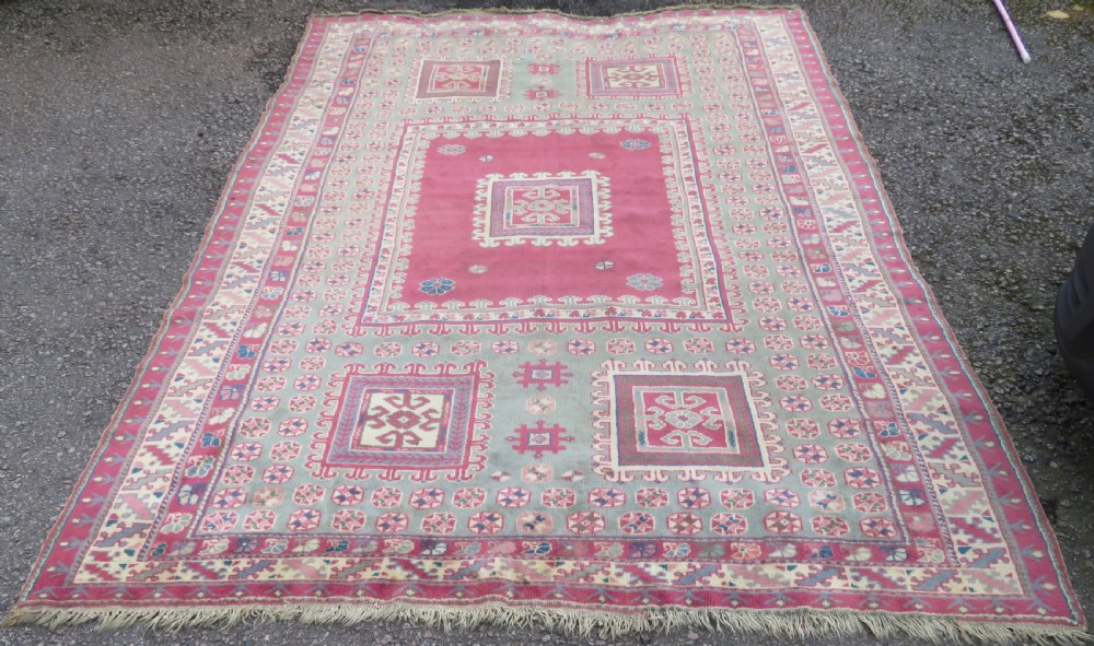 An antique Turkish Bergama wool carpet featuring a red central field surrounded by sage green areas with geometric Holbein square medallions and detailed borders. View II