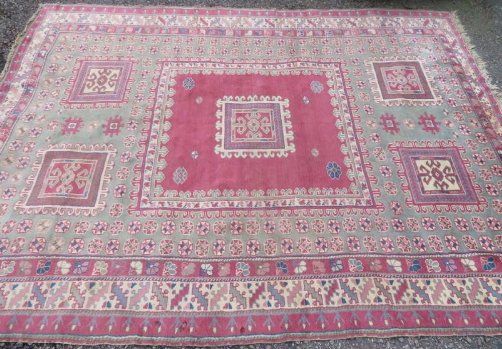 An antique Turkish Bergama wool carpet featuring a red central field surrounded by sage green areas with geometric Holbein square medallions and detailed borders. View III