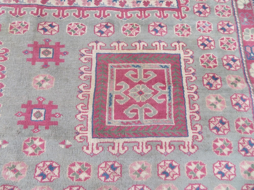 An antique Turkish Bergama wool carpet featuring a red central field surrounded by sage green areas with geometric Holbein square medallions and detailed borders. View XII