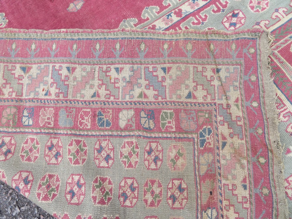 An antique Turkish Bergama wool carpet featuring a red central field surrounded by sage green areas with geometric Holbein square medallions and detailed borders. View XV
