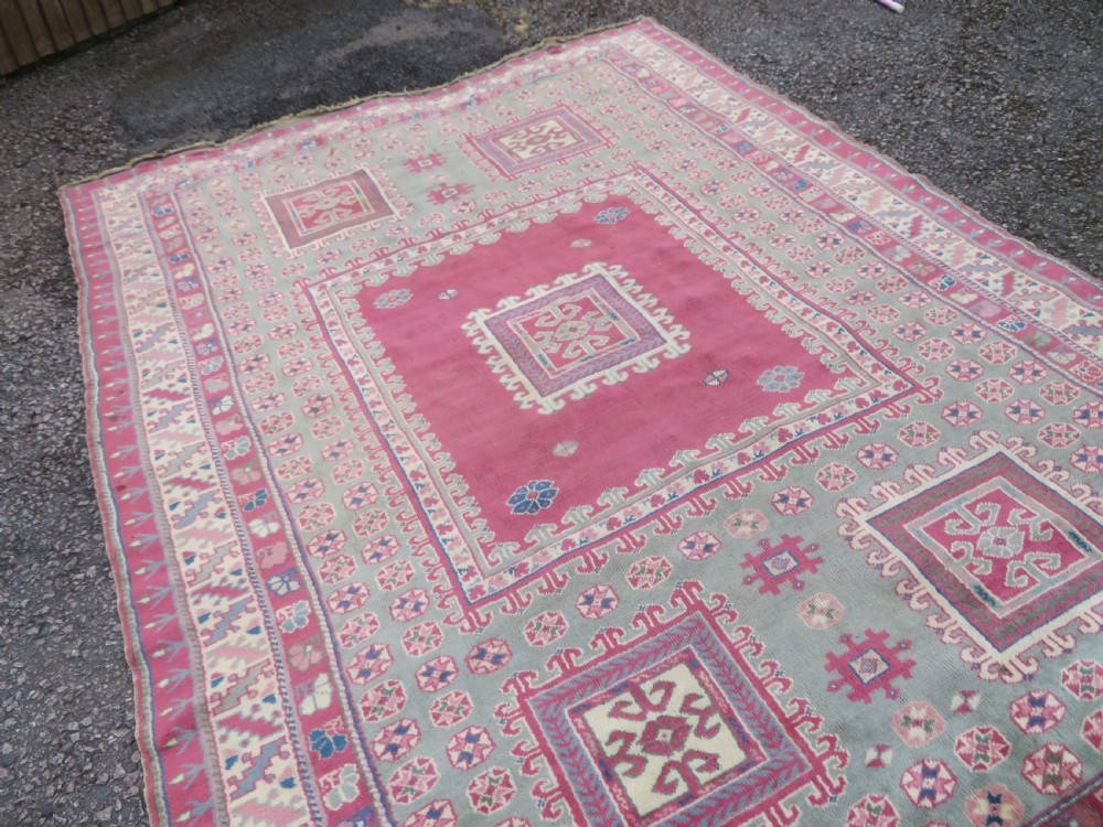 An antique Turkish Bergama wool carpet featuring a red central field surrounded by sage green areas with geometric Holbein square medallions and detailed borders. View XVIII