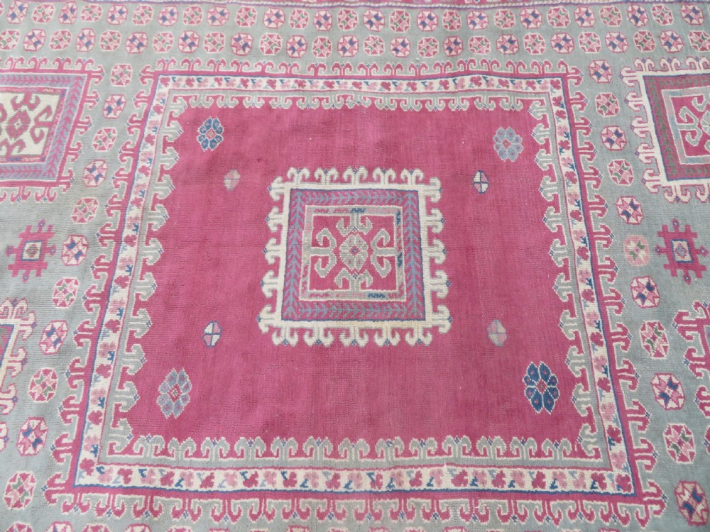 An antique Turkish Bergama wool carpet featuring a red central field surrounded by sage green areas with geometric Holbein square medallions and detailed borders. View XIX