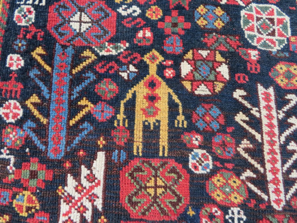An antique hand-knotted Qashqai wool rug featuring a dark navy field densely filled with geometric tribal motifs and stylised figures within a multi-tiered border. View III