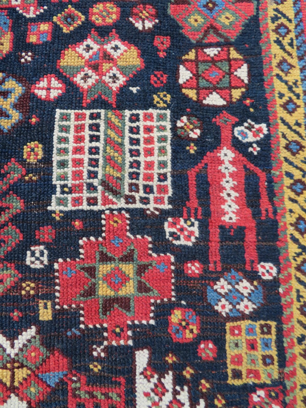An antique hand-knotted Qashqai wool rug featuring a dark navy field densely filled with geometric tribal motifs and stylised figures within a multi-tiered border. View V