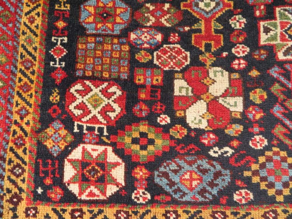 An antique hand-knotted Qashqai wool rug featuring a dark navy field densely filled with geometric tribal motifs and stylised figures within a multi-tiered border. View VIII