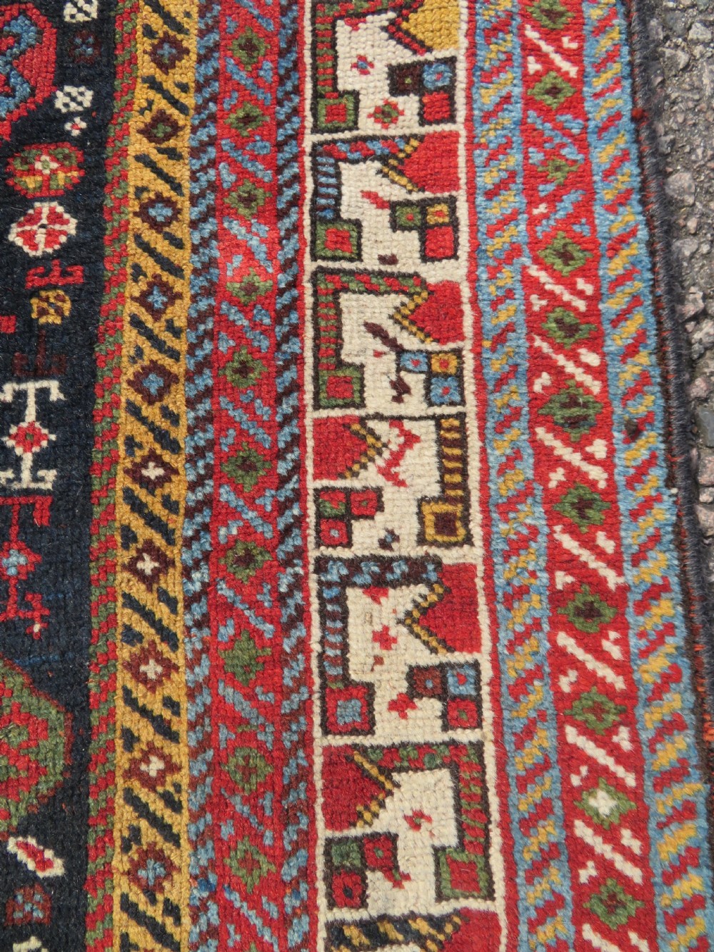 An antique hand-knotted Qashqai wool rug featuring a dark navy field densely filled with geometric tribal motifs and stylised figures within a multi-tiered border. View X