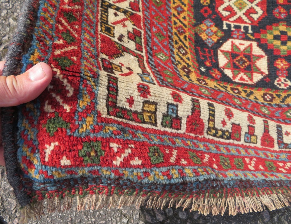 An antique hand-knotted Qashqai wool rug featuring a dark navy field densely filled with geometric tribal motifs and stylised figures within a multi-tiered border. View XI