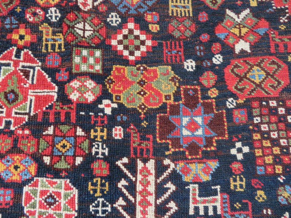 An antique hand-knotted Qashqai wool rug featuring a dark navy field densely filled with geometric tribal motifs and stylised figures within a multi-tiered border. View XVII