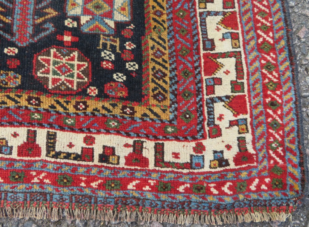 An antique hand-knotted Qashqai wool rug featuring a dark navy field densely filled with geometric tribal motifs and stylised figures within a multi-tiered border. View XIX
