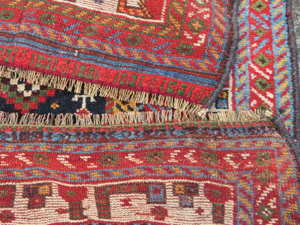 An antique hand-knotted Qashqai wool rug featuring a dark navy field densely filled with geometric tribal motifs and stylised figures within a multi-tiered border. View XXIII