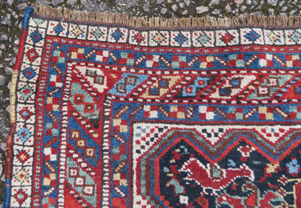 An antique South West Persian Khamseh wool rug with repeating geometric diamond medallions in deep red and indigo blue tones. View VII