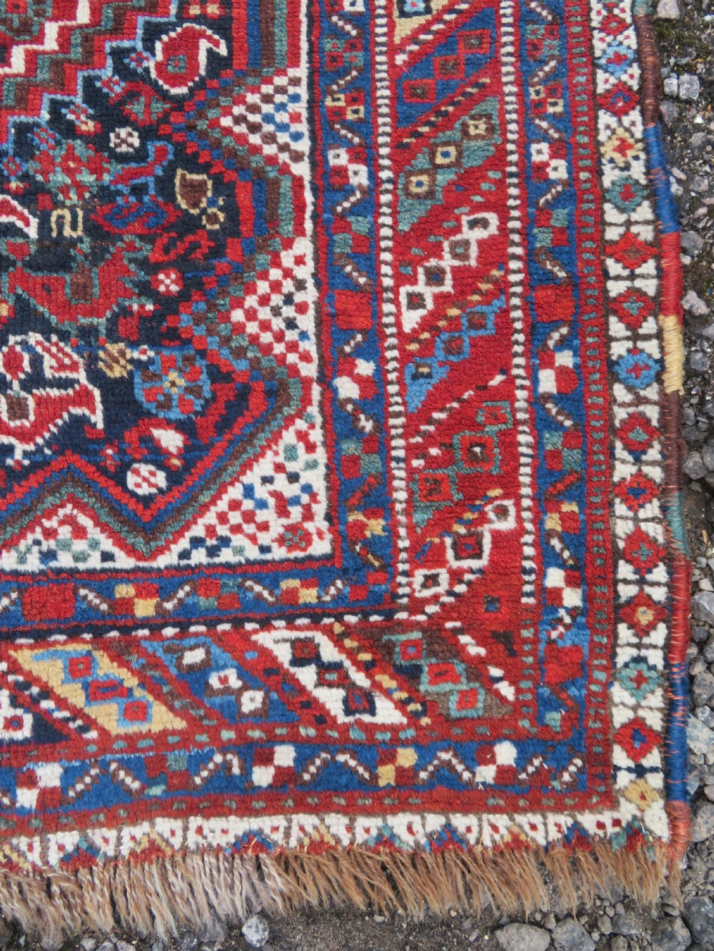 An antique South West Persian Khamseh wool rug with repeating geometric diamond medallions in deep red and indigo blue tones. View XIV