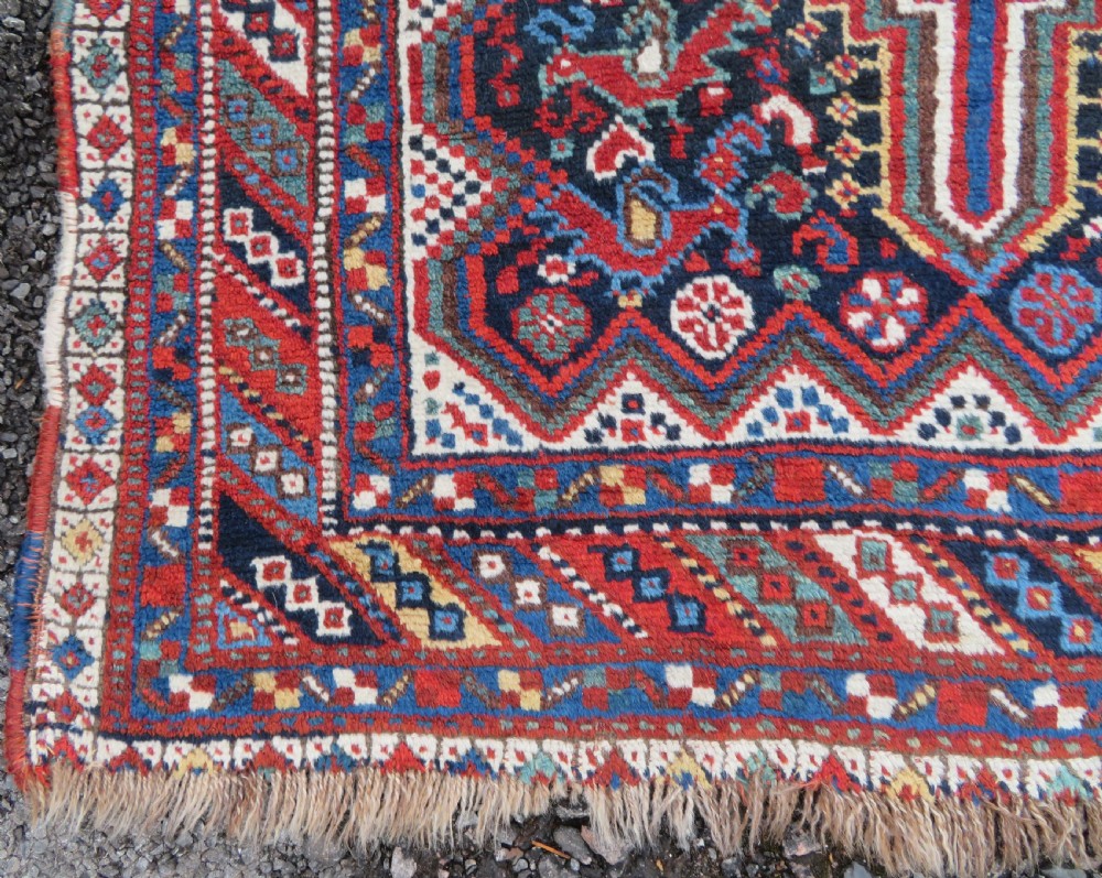 An antique South West Persian Khamseh wool rug with repeating geometric diamond medallions in deep red and indigo blue tones. View XV