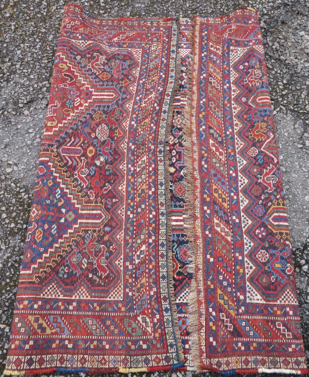 An antique South West Persian Khamseh wool rug with repeating geometric diamond medallions in deep red and indigo blue tones. View XVIII