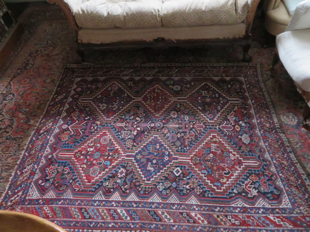 An antique South West Persian Khamseh wool rug with repeating geometric diamond medallions in deep red and indigo blue tones. View XXII
