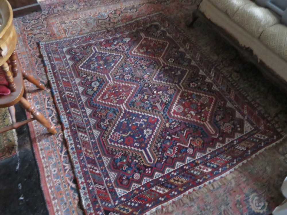 An antique South West Persian Khamseh wool rug with repeating geometric diamond medallions in deep red and indigo blue tones. View XXIII