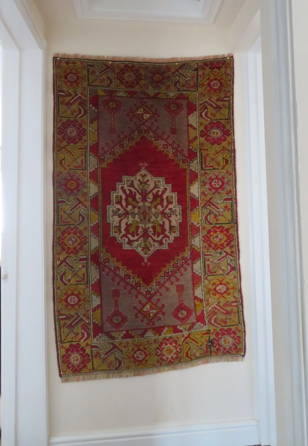 An early 19th-century Central Anatolian Konya rug featuring a central red field with a stepped diamond medallion surrounded by mustard-yellow geometric borders.