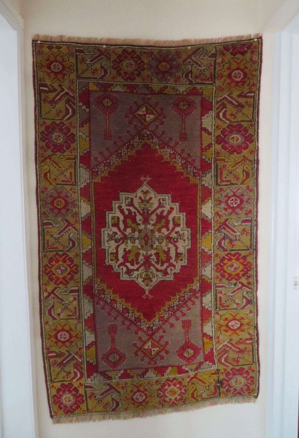 An early 19th-century Central Anatolian Konya rug featuring a central red field with a stepped diamond medallion surrounded by mustard-yellow geometric borders. View II