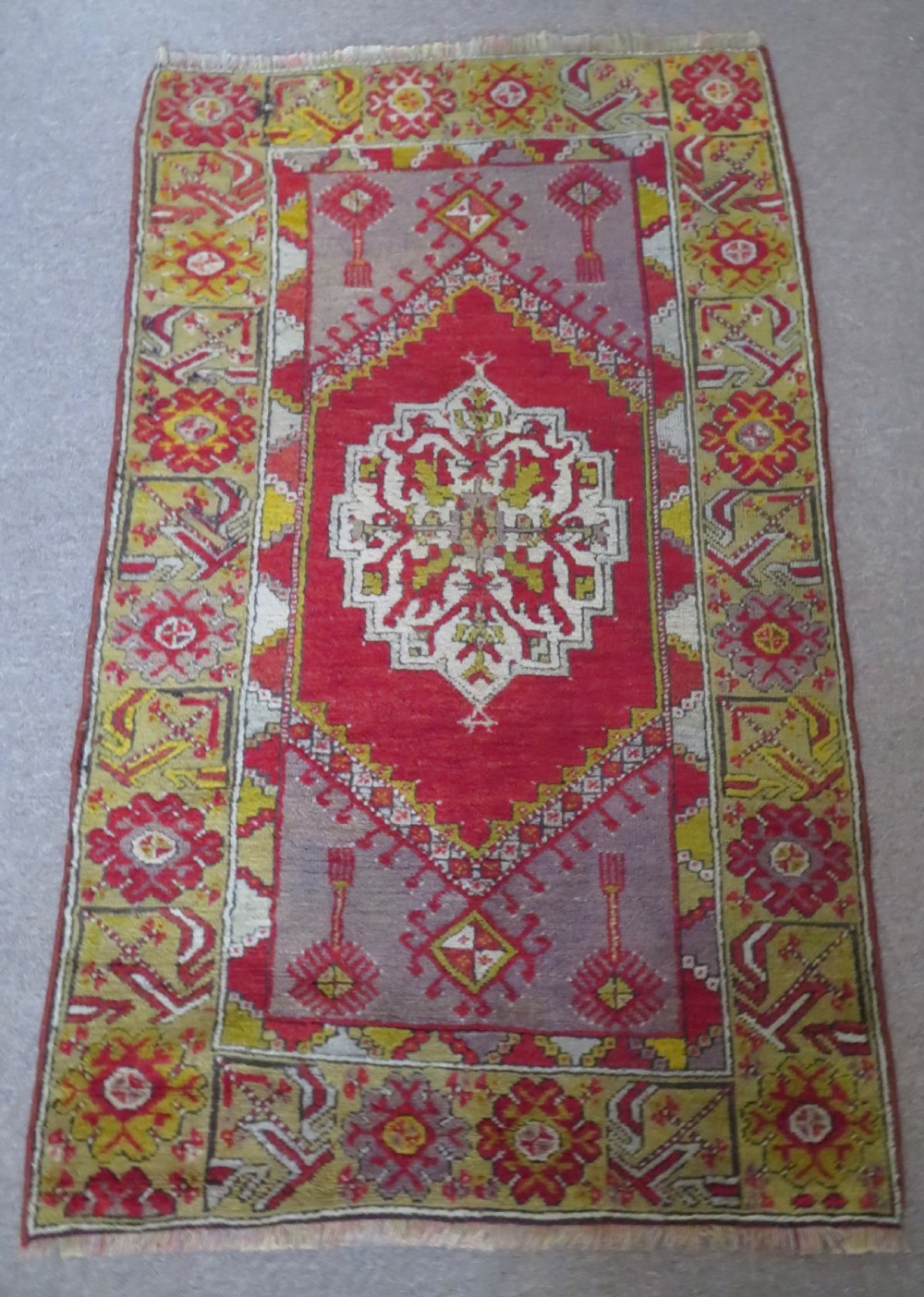 An early 19th-century Central Anatolian Konya rug featuring a central red field with a stepped diamond medallion surrounded by mustard-yellow geometric borders. View III