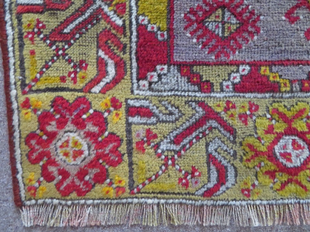 An early 19th-century Central Anatolian Konya rug featuring a central red field with a stepped diamond medallion surrounded by mustard-yellow geometric borders. View VIII