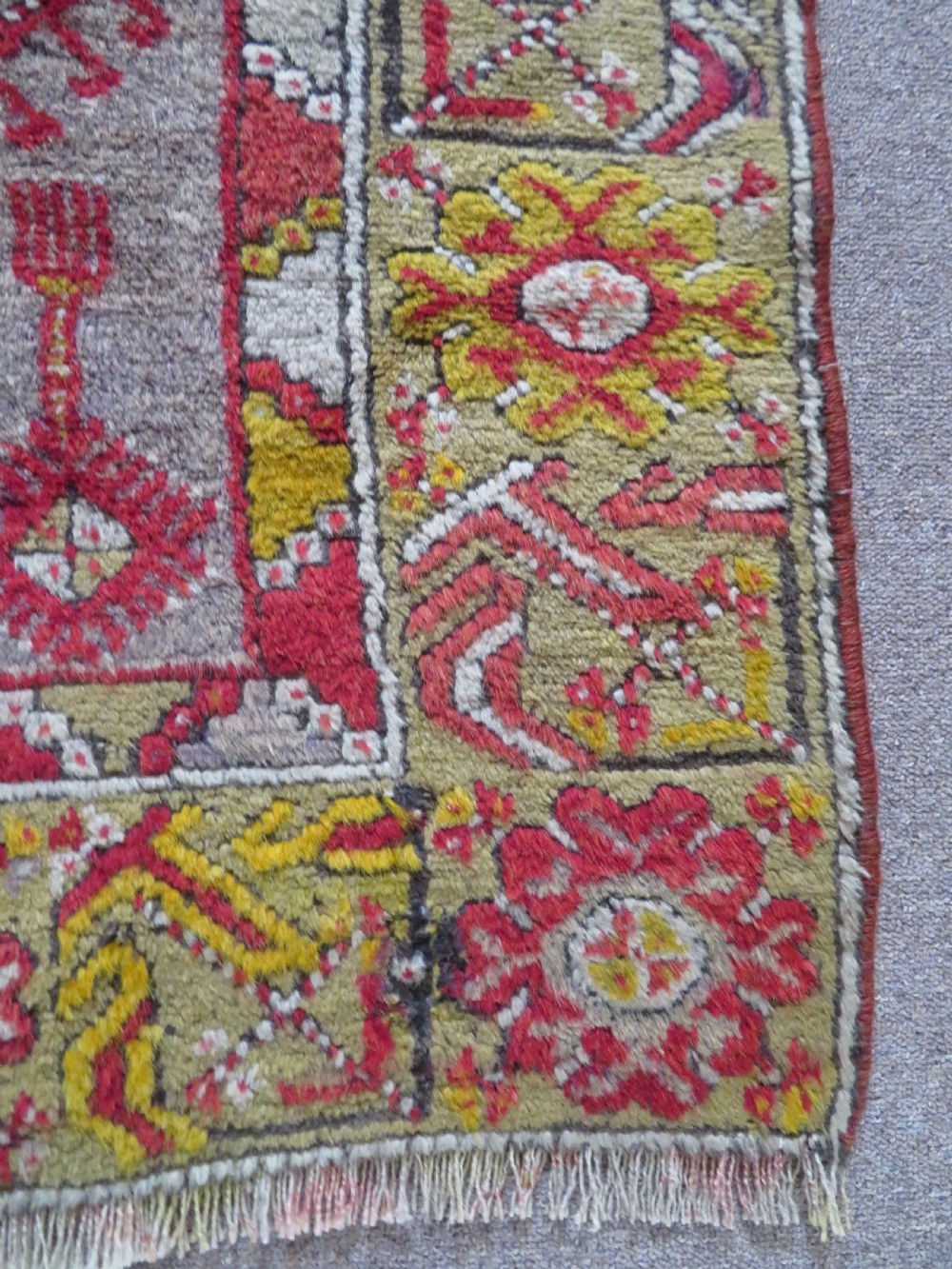 An early 19th-century Central Anatolian Konya rug featuring a central red field with a stepped diamond medallion surrounded by mustard-yellow geometric borders. View IX