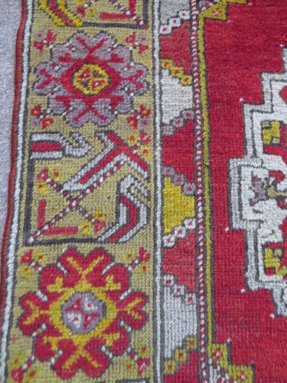 An early 19th-century Central Anatolian Konya rug featuring a central red field with a stepped diamond medallion surrounded by mustard-yellow geometric borders. View XI