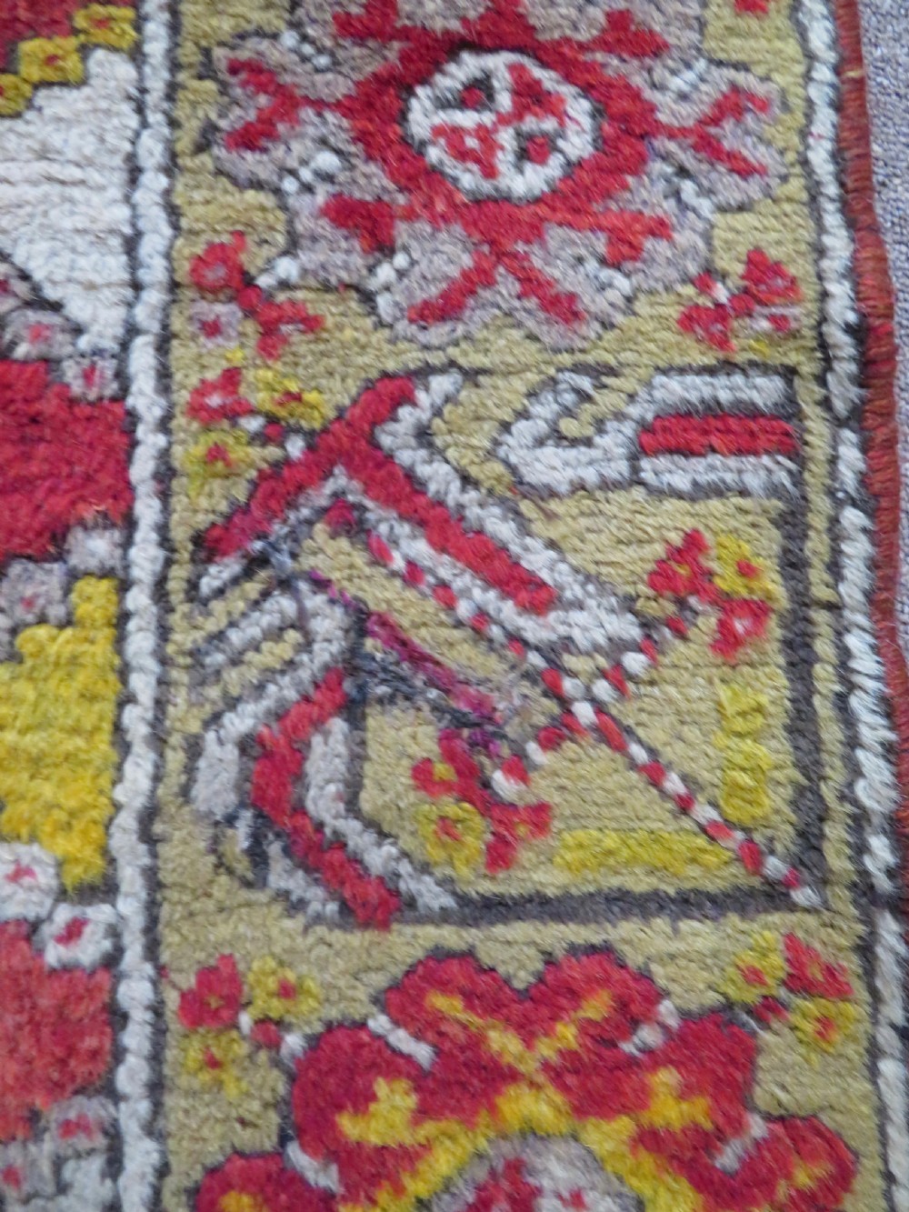 An early 19th-century Central Anatolian Konya rug featuring a central red field with a stepped diamond medallion surrounded by mustard-yellow geometric borders. View XIII
