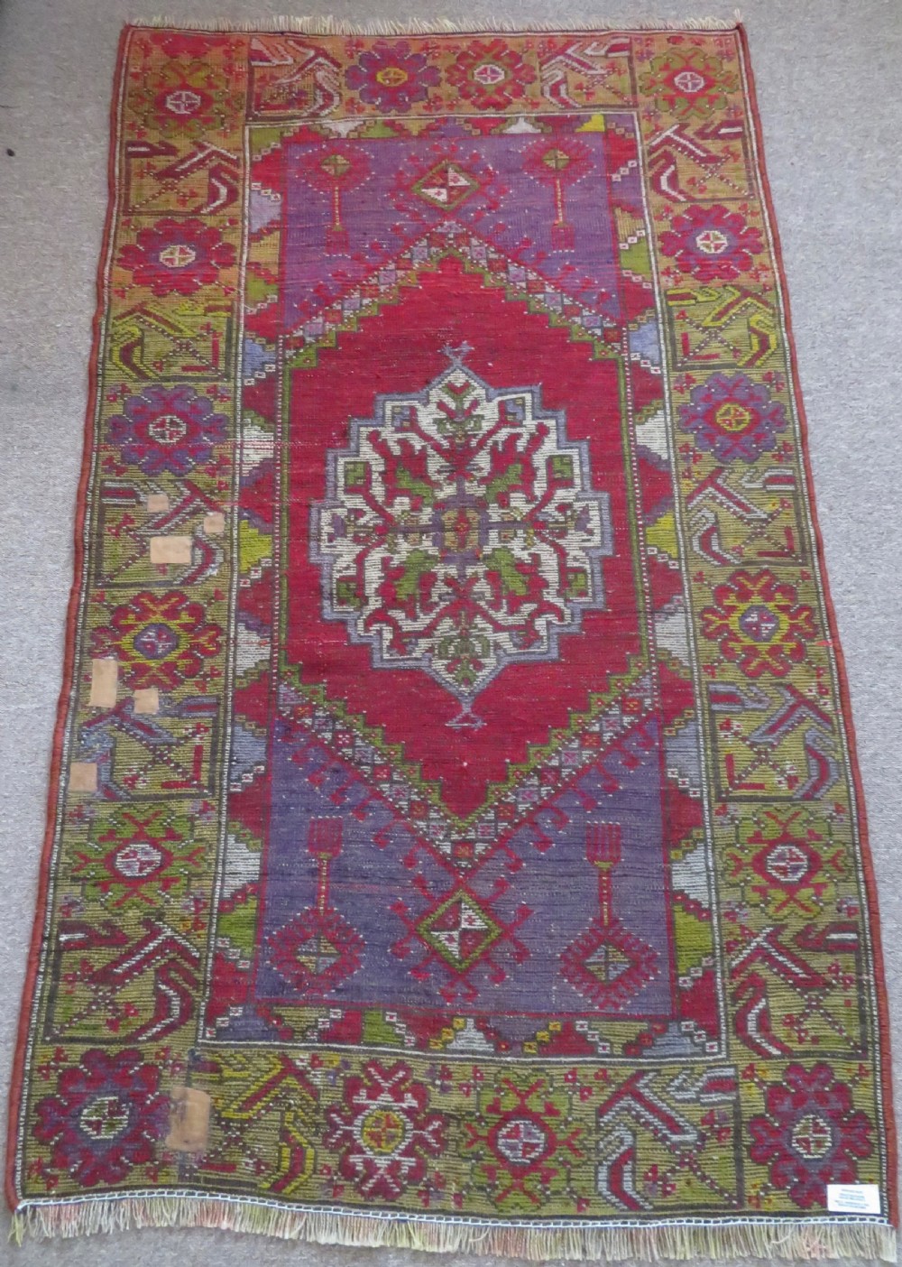 An early 19th-century Central Anatolian Konya rug featuring a central red field with a stepped diamond medallion surrounded by mustard-yellow geometric borders. View XV