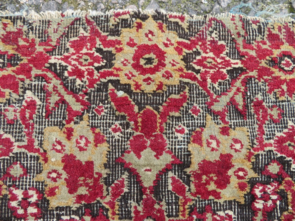 A square-shaped North Indian Mughal wool carpet fragment featuring detailed crimson and dark brown floral scrollwork. View III
