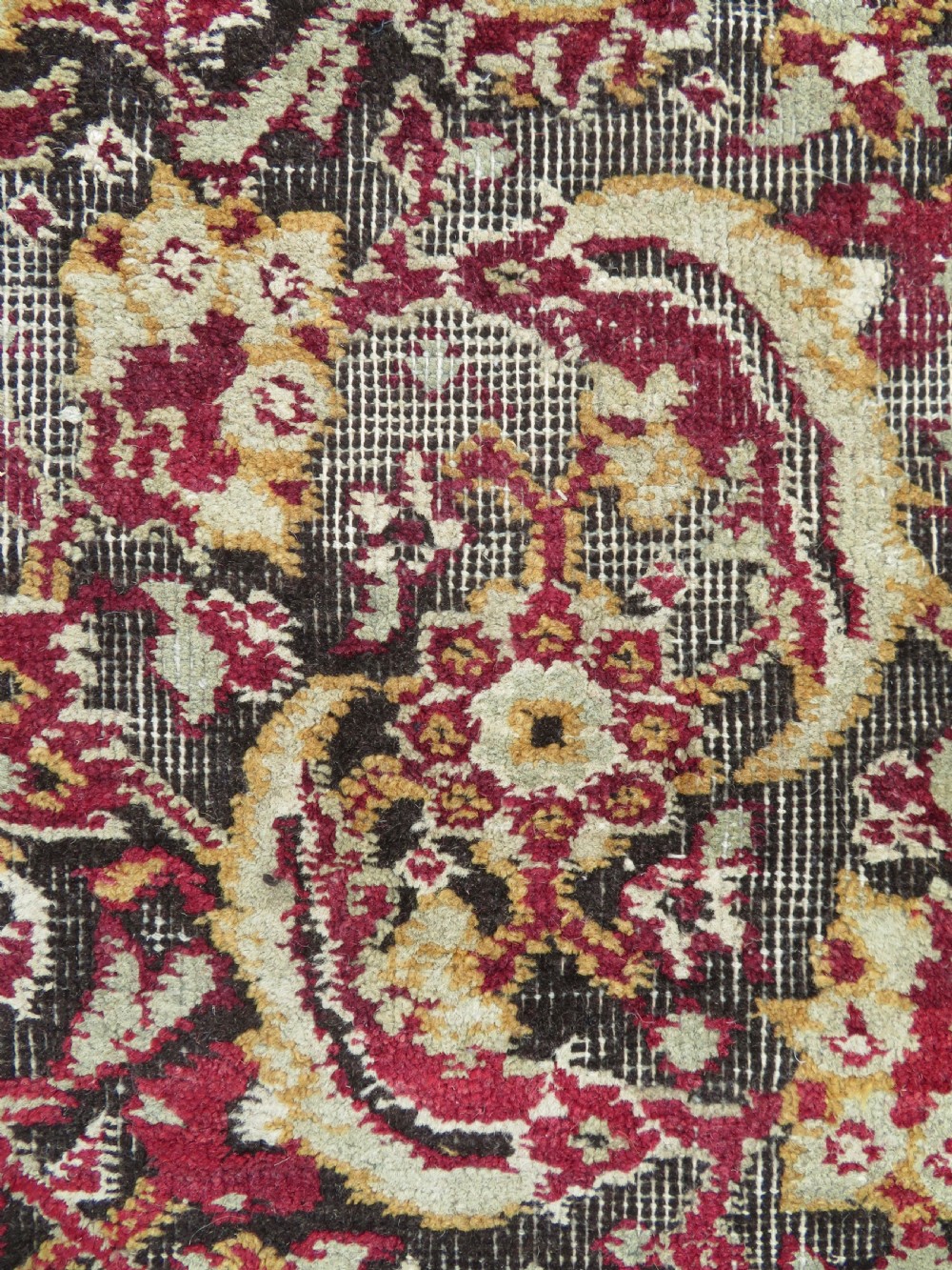 A square-shaped North Indian Mughal wool carpet fragment featuring detailed crimson and dark brown floral scrollwork. View IV