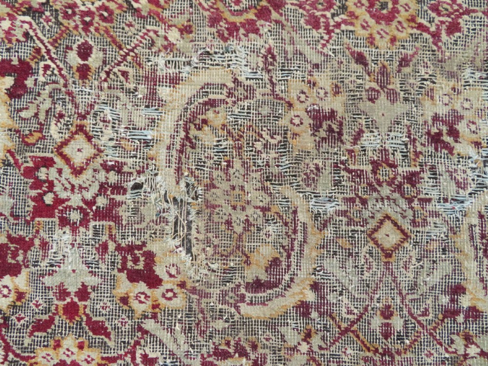 A square-shaped North Indian Mughal wool carpet fragment featuring detailed crimson and dark brown floral scrollwork. View IX