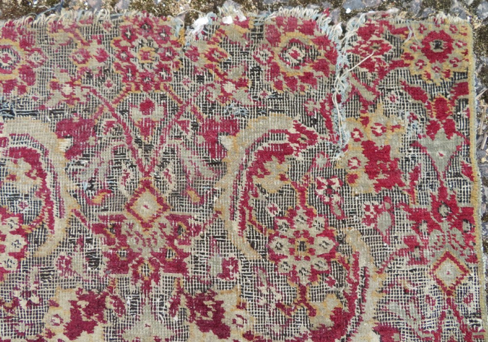 A square-shaped North Indian Mughal wool carpet fragment featuring detailed crimson and dark brown floral scrollwork. View X