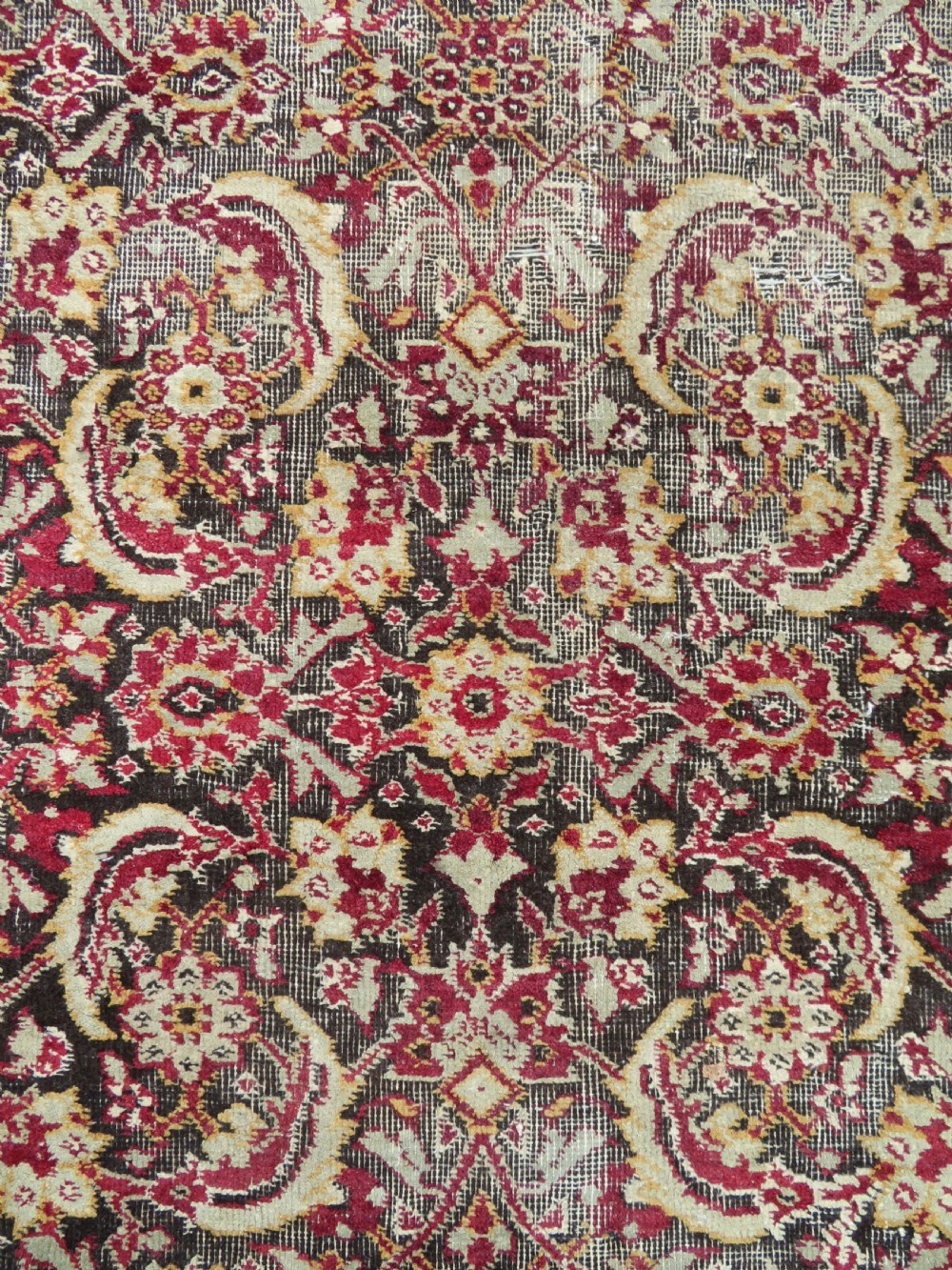 A square-shaped North Indian Mughal wool carpet fragment featuring detailed crimson and dark brown floral scrollwork. View XI