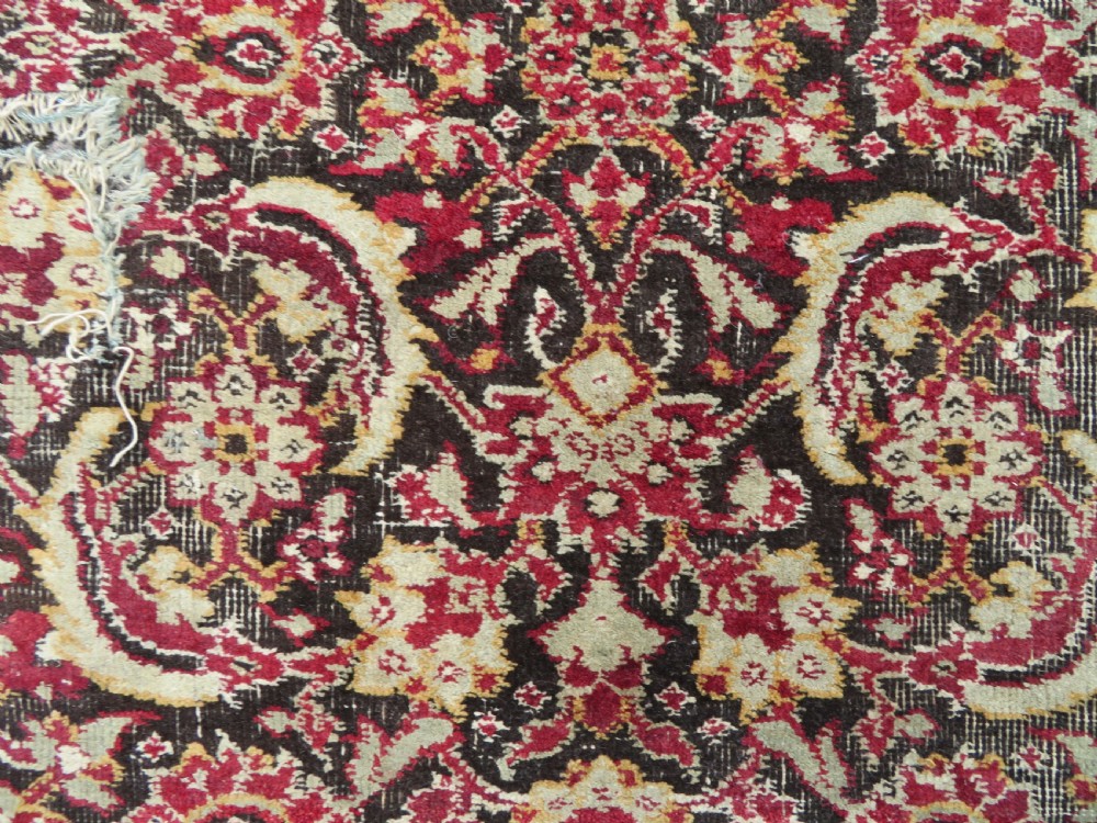 A square-shaped North Indian Mughal wool carpet fragment featuring detailed crimson and dark brown floral scrollwork. View XII