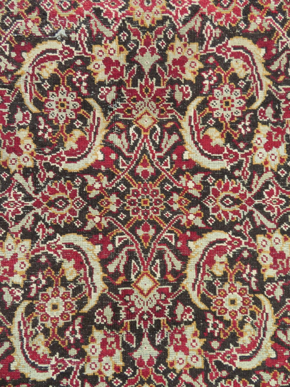 A square-shaped North Indian Mughal wool carpet fragment featuring detailed crimson and dark brown floral scrollwork. View XV