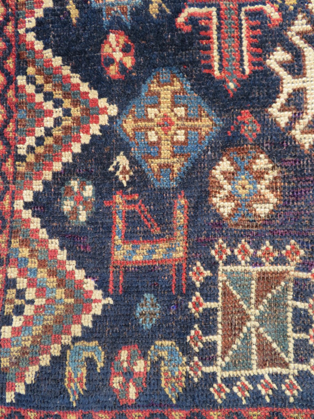 An antique hand-knotted Luri wool rug featuring three central diamond medallions surrounded by geometric tribal symbols on a dark navy field with a red border. View IV