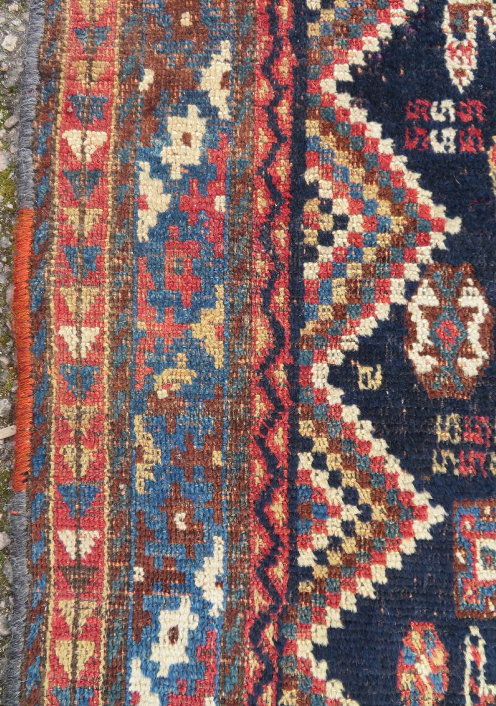 An antique hand-knotted Luri wool rug featuring three central diamond medallions surrounded by geometric tribal symbols on a dark navy field with a red border. View X