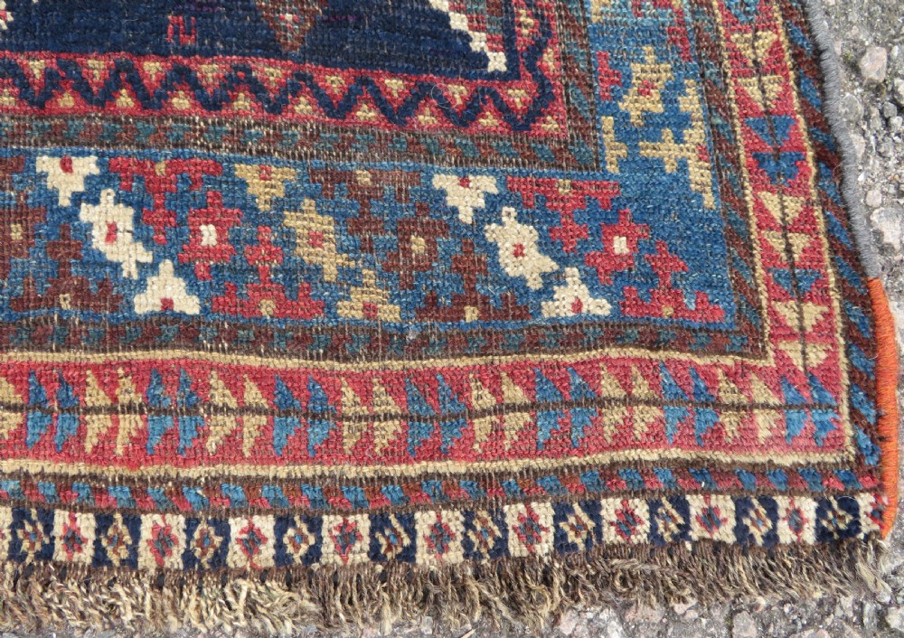 An antique hand-knotted Luri wool rug featuring three central diamond medallions surrounded by geometric tribal symbols on a dark navy field with a red border. View XI