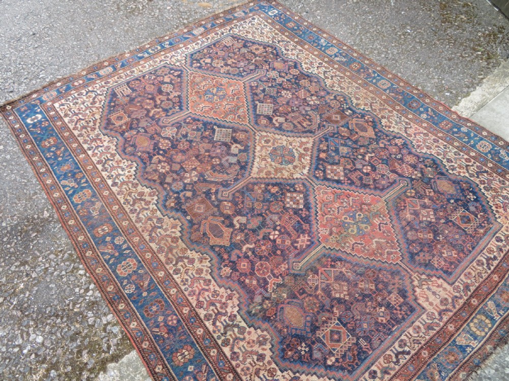 A hand-knotted antique Khamseh wool rug featuring three stepped diamond medallions surrounded by dense floral and avian tribal motifs on a dark navy blue field with multi-tiered geometric borders. View II