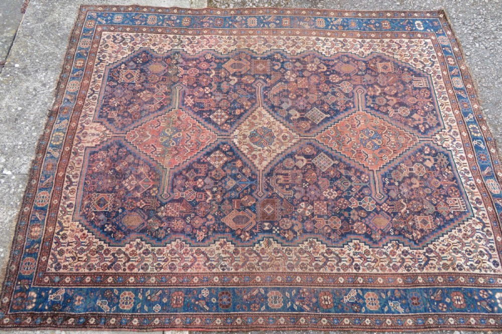 A hand-knotted antique Khamseh wool rug featuring three stepped diamond medallions surrounded by dense floral and avian tribal motifs on a dark navy blue field with multi-tiered geometric borders. View III