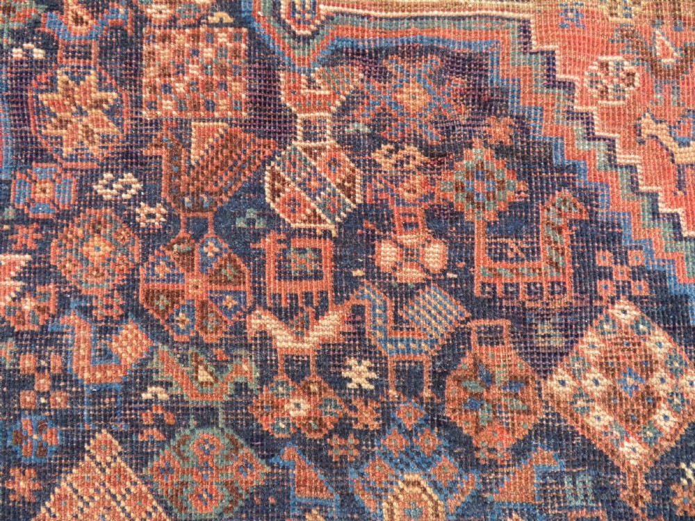 A hand-knotted antique Khamseh wool rug featuring three stepped diamond medallions surrounded by dense floral and avian tribal motifs on a dark navy blue field with multi-tiered geometric borders. View VII
