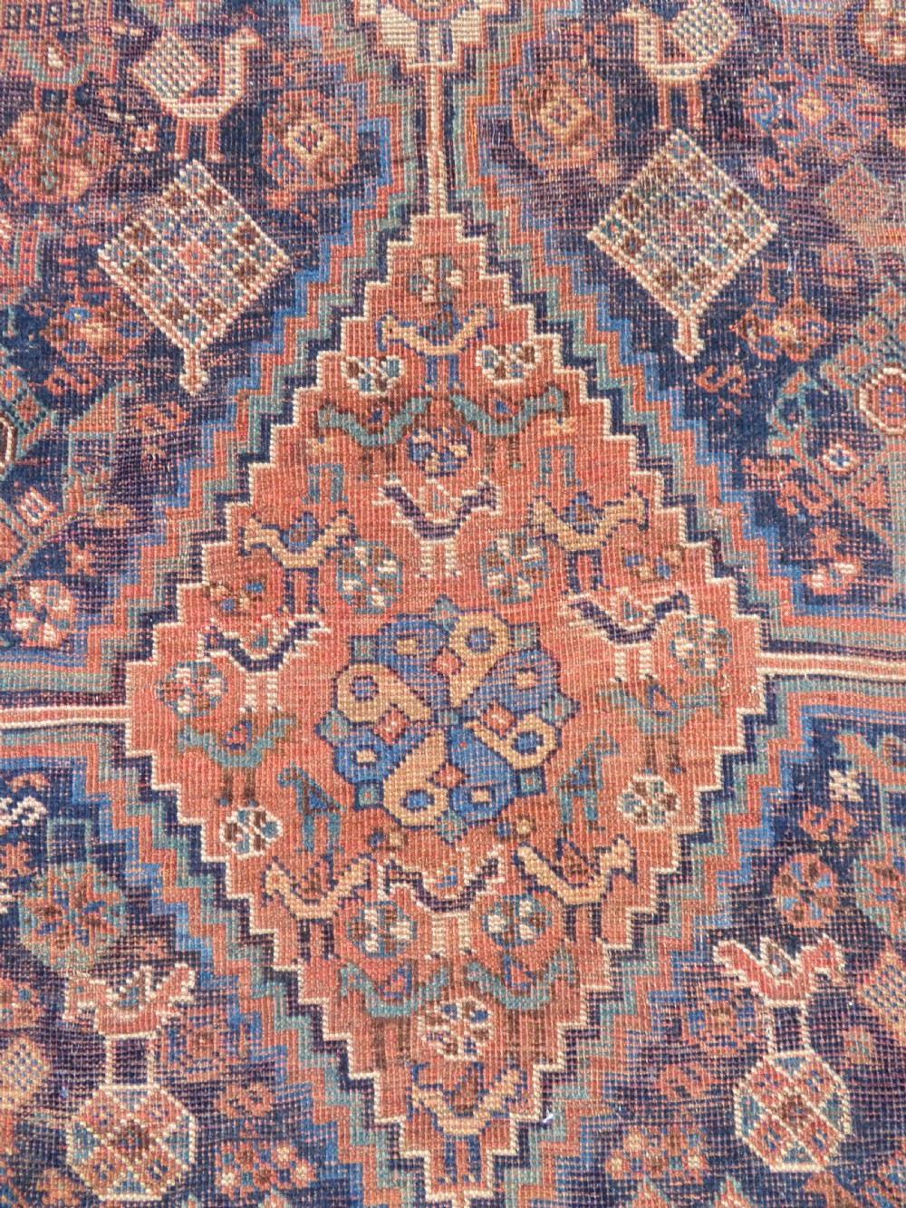 A hand-knotted antique Khamseh wool rug featuring three stepped diamond medallions surrounded by dense floral and avian tribal motifs on a dark navy blue field with multi-tiered geometric borders. View XI
