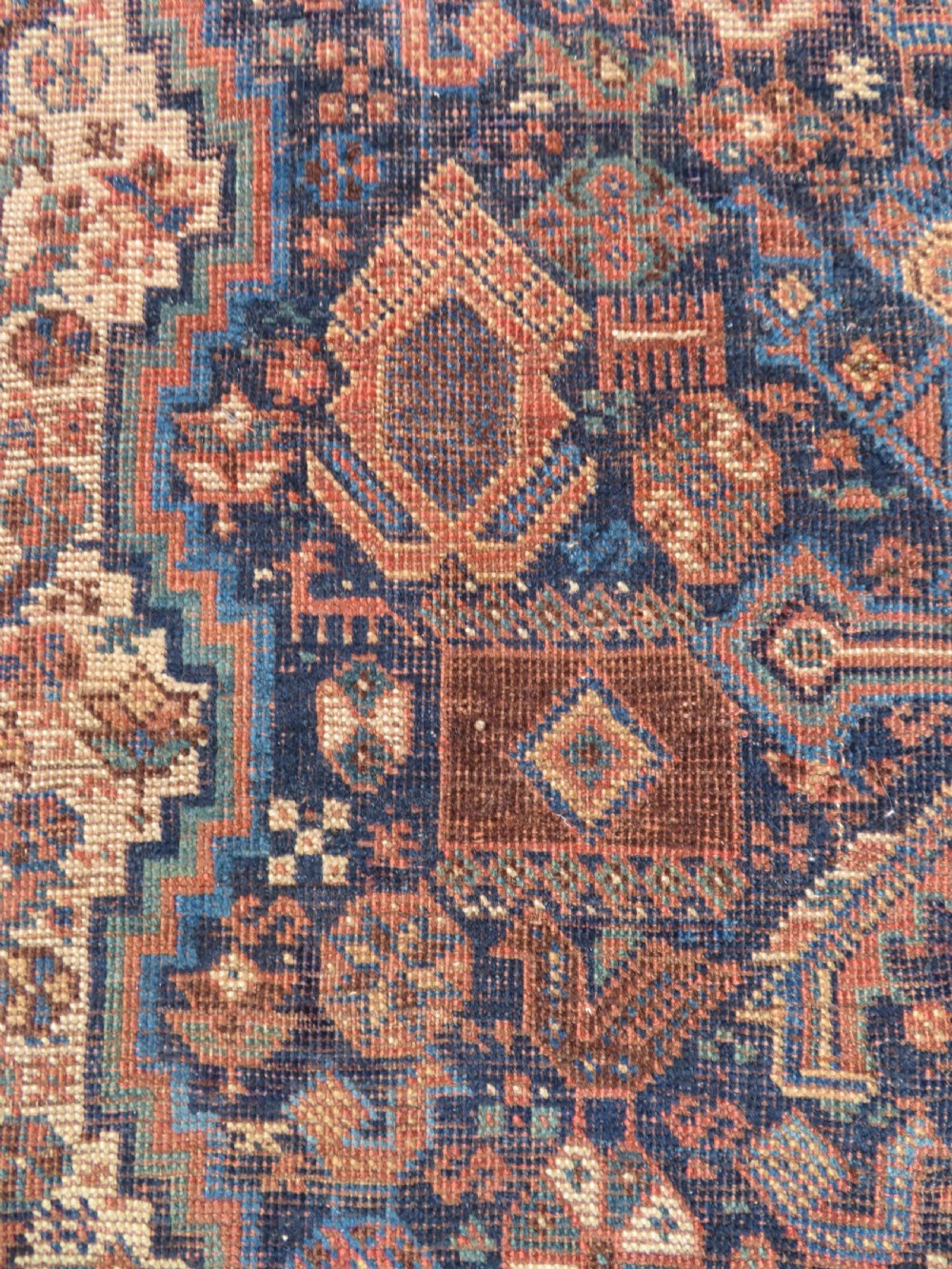 A hand-knotted antique Khamseh wool rug featuring three stepped diamond medallions surrounded by dense floral and avian tribal motifs on a dark navy blue field with multi-tiered geometric borders. View XII