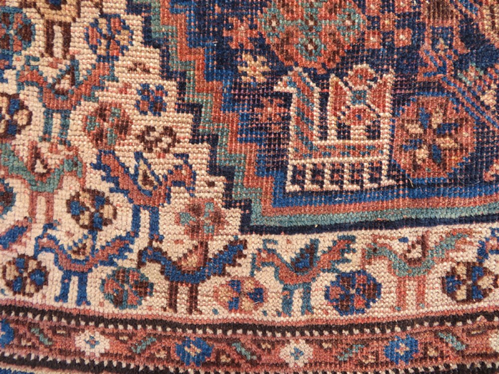 A hand-knotted antique Khamseh wool rug featuring three stepped diamond medallions surrounded by dense floral and avian tribal motifs on a dark navy blue field with multi-tiered geometric borders. View XIII