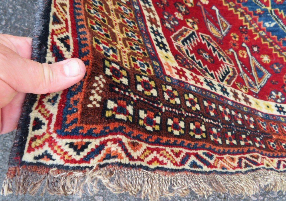 An antique Qashqai tribal wool rug featuring a deep blue central field with geometric bird motifs, red spandrels, and a complex multi-band border. View X
