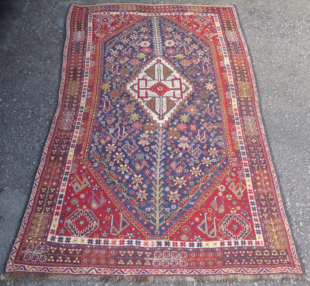 An antique Qashqai tribal wool rug featuring a deep blue central field with geometric bird motifs, red spandrels, and a complex multi-band border. View XII