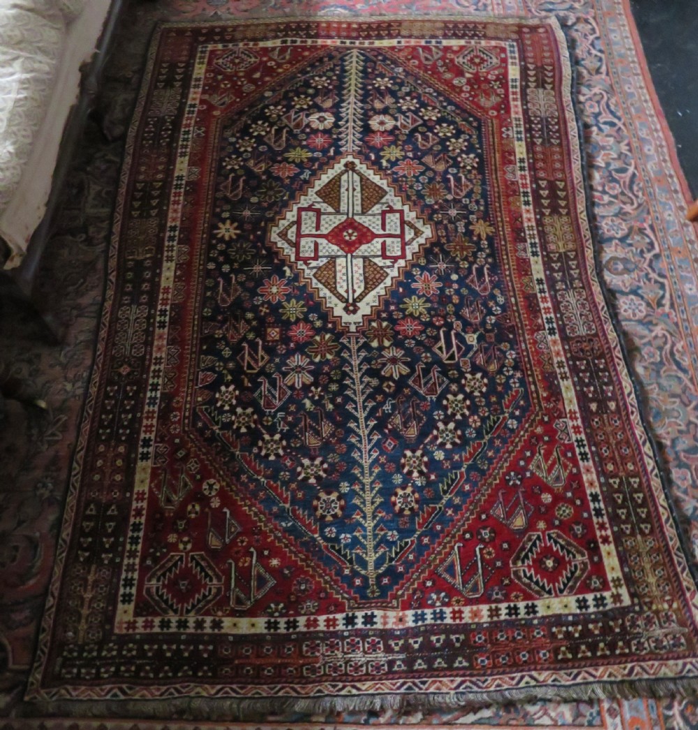 An antique Qashqai tribal wool rug featuring a deep blue central field with geometric bird motifs, red spandrels, and a complex multi-band border. View XV