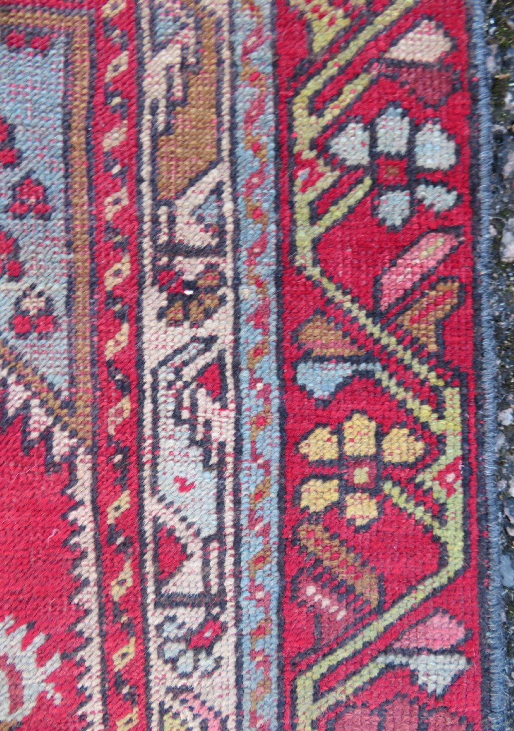 An antique hand-knotted Anatolian wool rug featuring a bold red field, a central geometric medallion in green and yellow, and detailed multi-patterned borders. View VIII